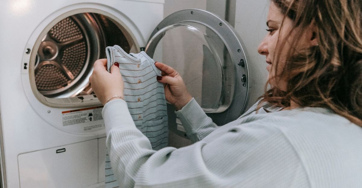 Una donna tira fuori dalla lavatrice dei vestiti da bambino