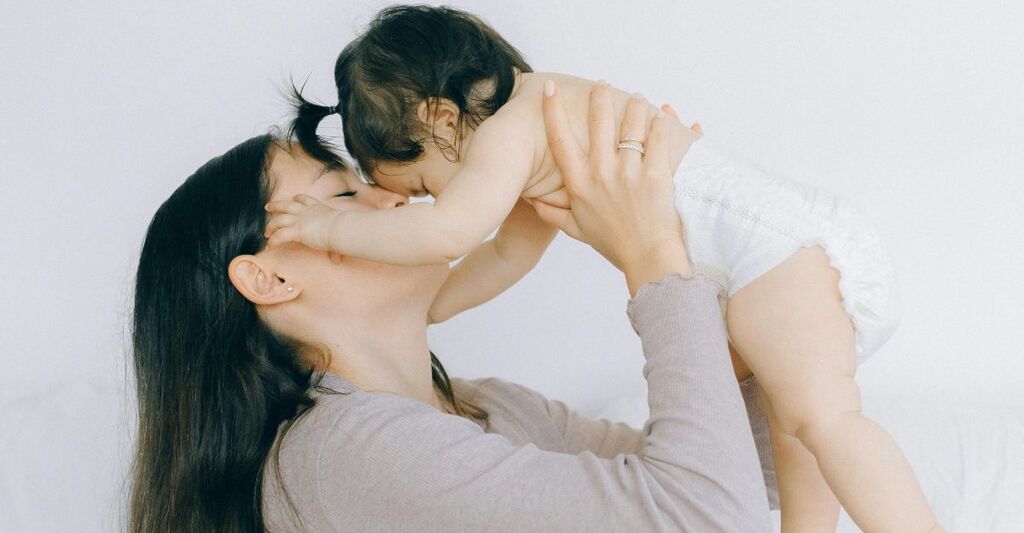 Mamma con neonata in braccio mentre la coccola