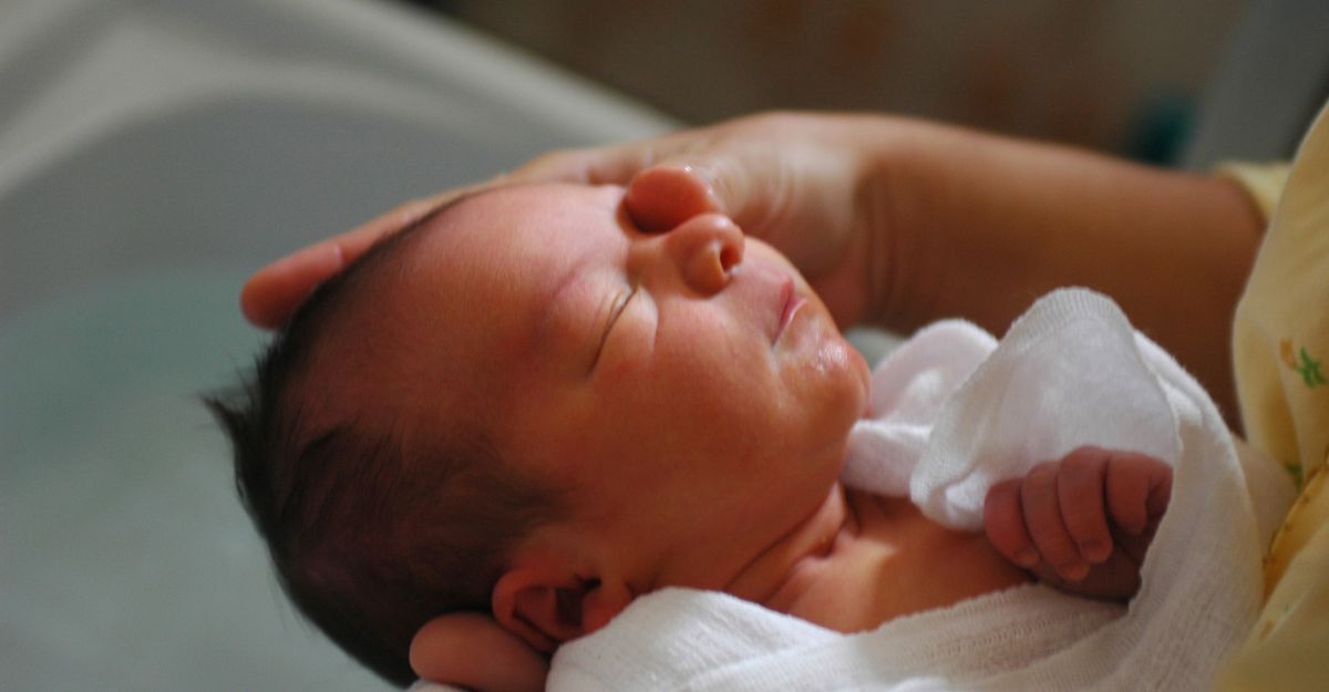 neonato tenuto in braccio da un adulto