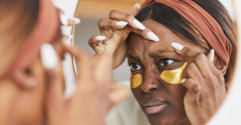 Una donna con un brufolo si guarda allo specchio