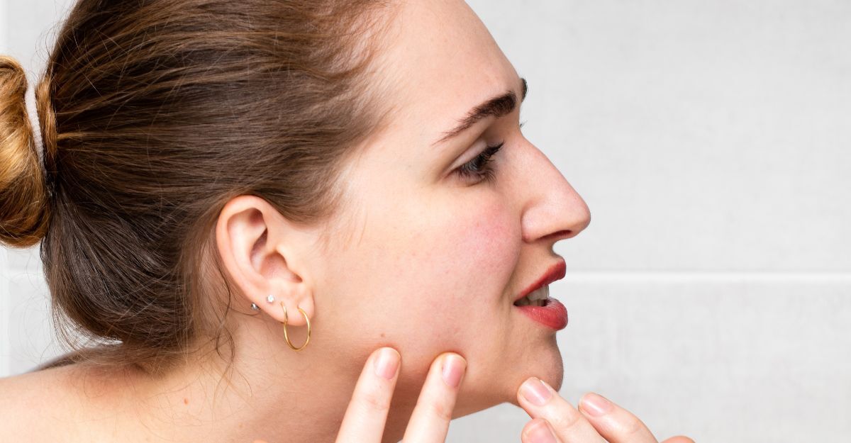 Una donna con un brufolo si guarda allo specchio