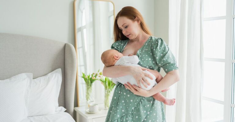 Mamma che allatta un neonato in piedi