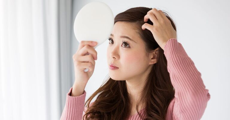Ragazza che si controlla il cuoio capelluto allo specchio