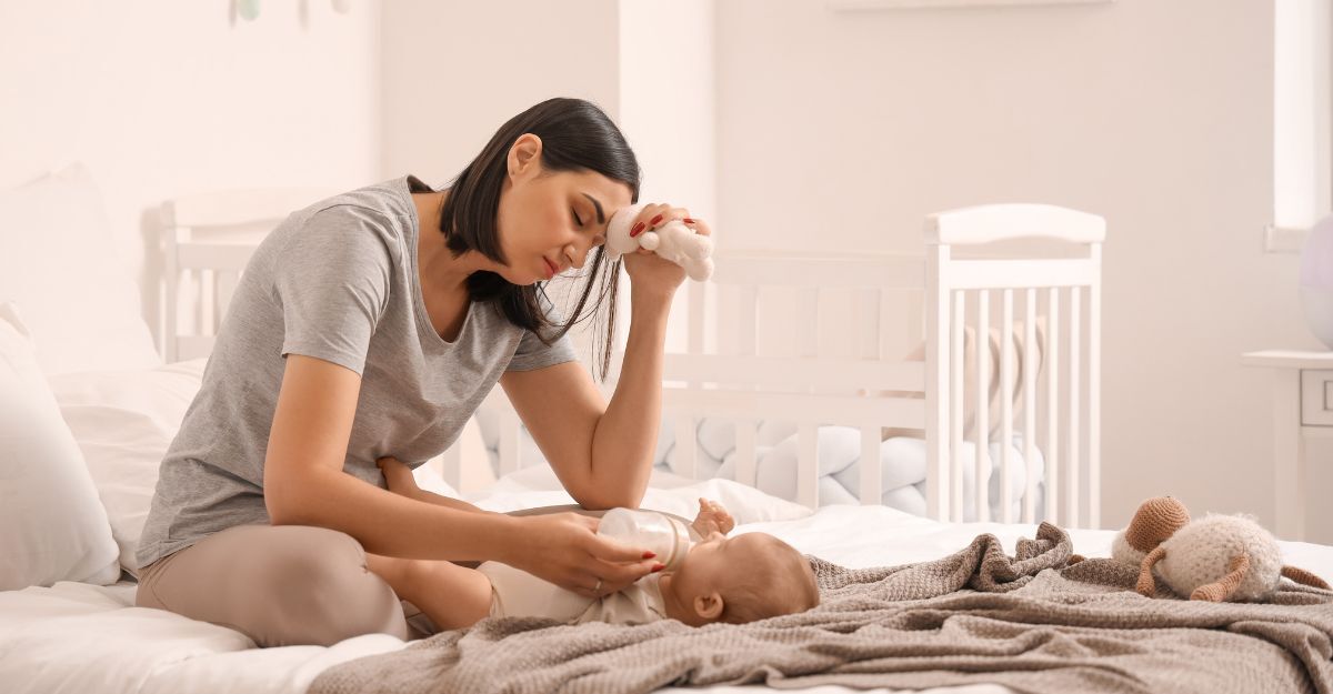 mamma stanca seduta sul letto con il suo neonato
