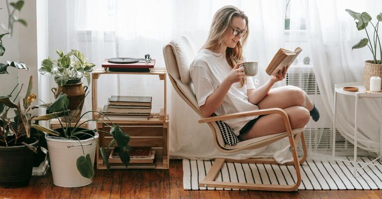 Ragazza che legge un libro in poltrona