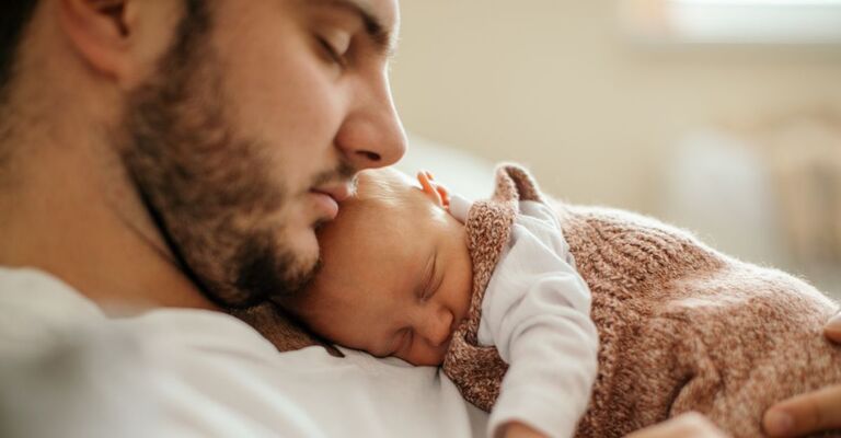 papà riposa con il suo neonato in braccio