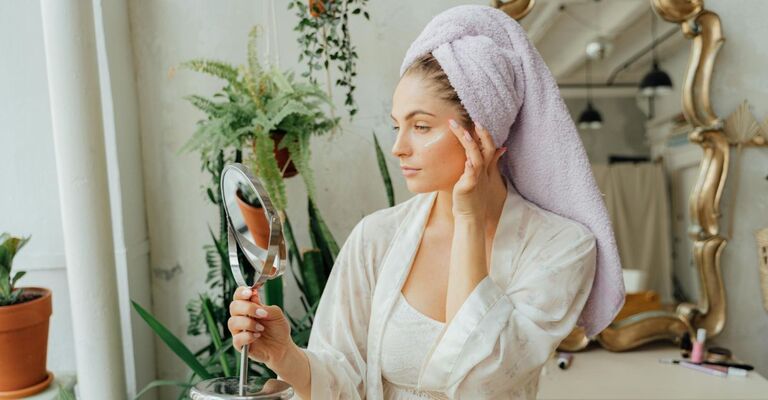 Ragazza si specchia e si mette la crema