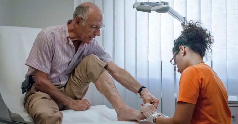 Paziente anziano su lettino con podologa