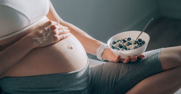Donna incinta che mangia una ciotola di ricotta e mirtilli