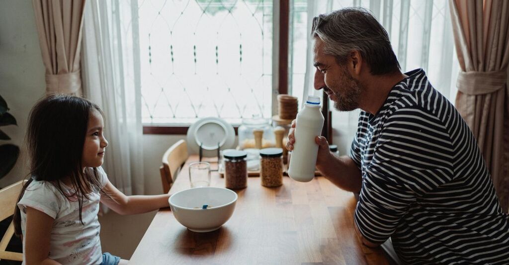 Papà che controlla il latte per la colazione della figlia