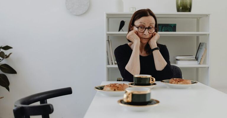 Donna seduta che guarda due tazze sul tavolo