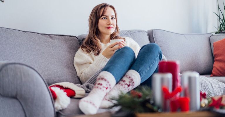 Donna seduta sul divano che guarda film di Natale