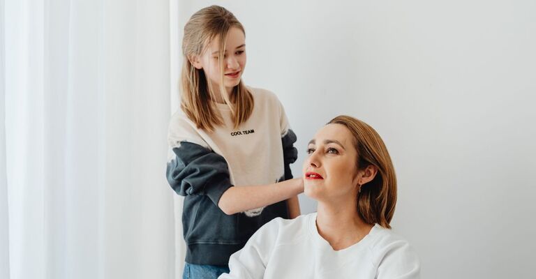 Bambina che acconcia i capelli alla mamma
