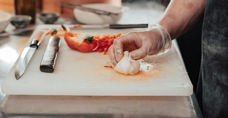 Persona taglia peperoni e aglio sul tagliere