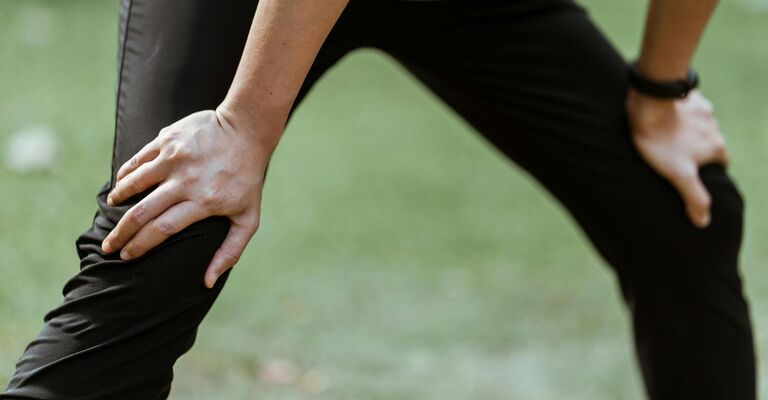 Persona con gambe aperte che si appoggia sulle ginocchia