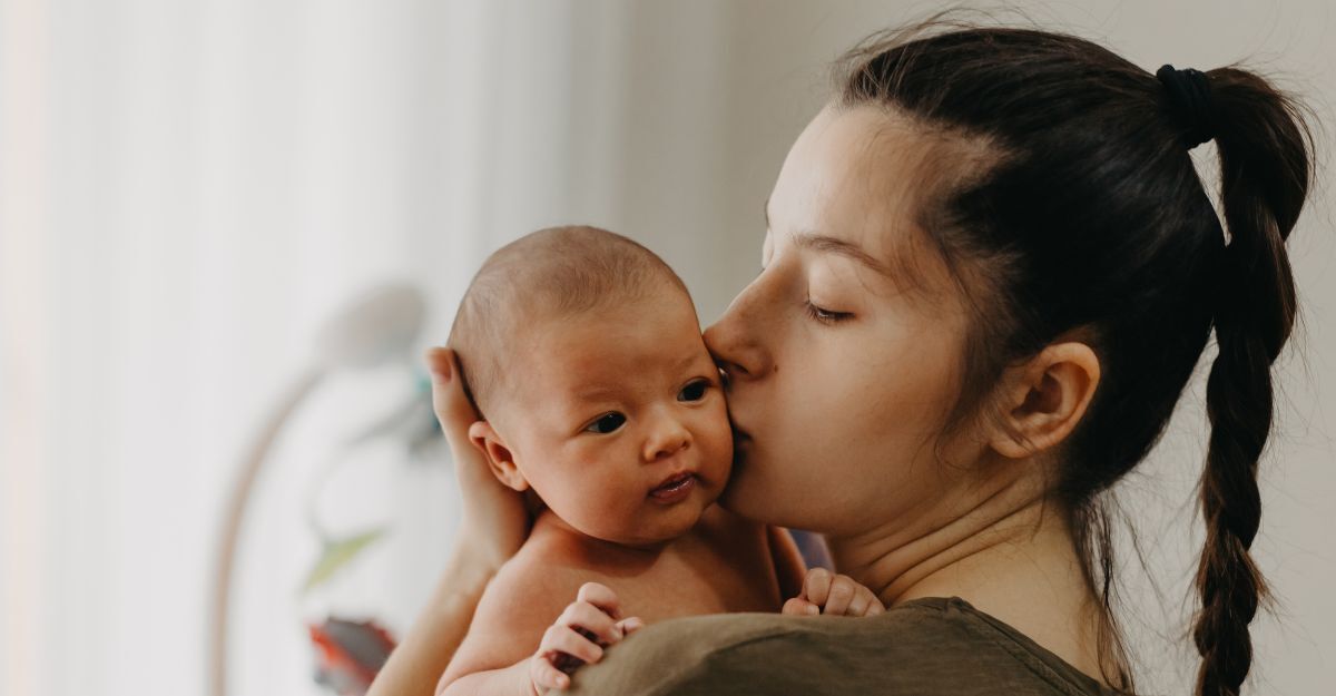 Giovane donna con neonato in braccio mentre lo bacia