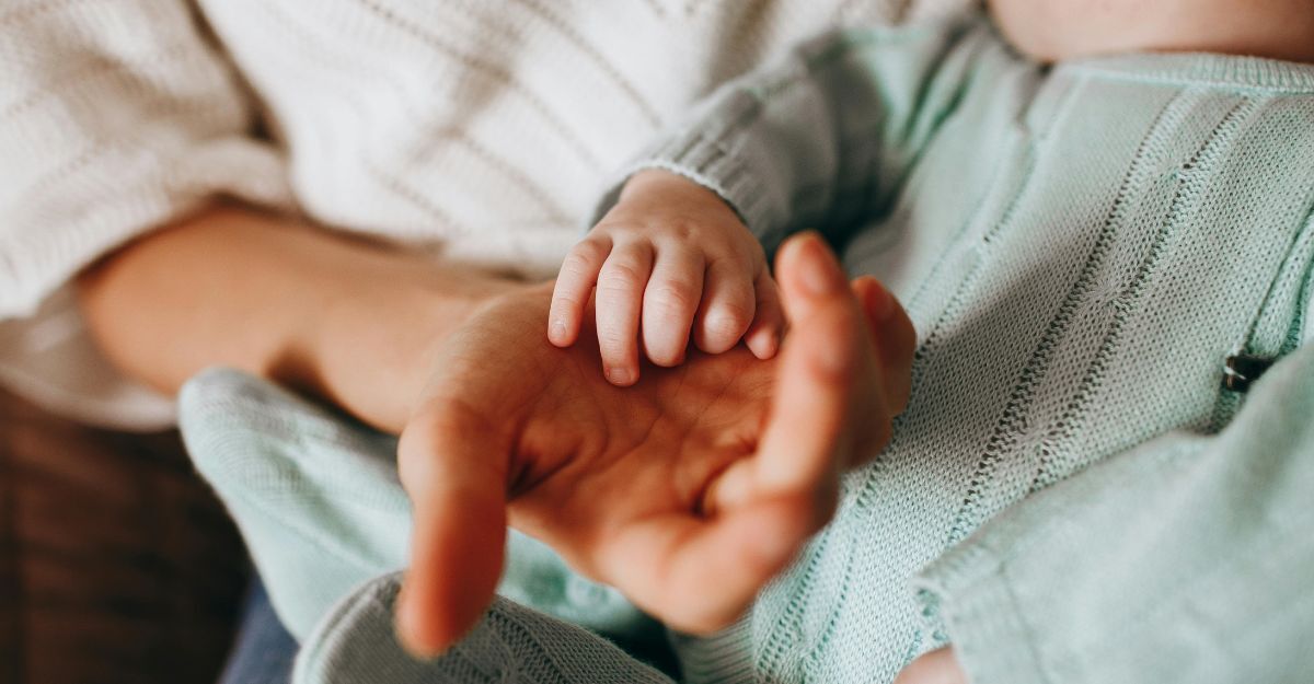 Mano di adulta con mano di neonato appoggiata