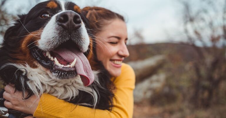 Una ragazza abbracciata al suo cane sorridente