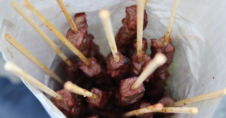 Primo piano di arrosticini dentro un cartoccio