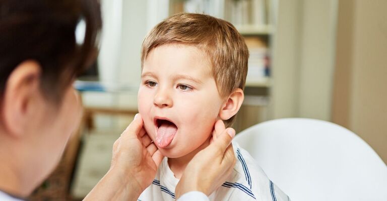 Un bambino con la bocca aperta si fa visitare le tonsille dal medico