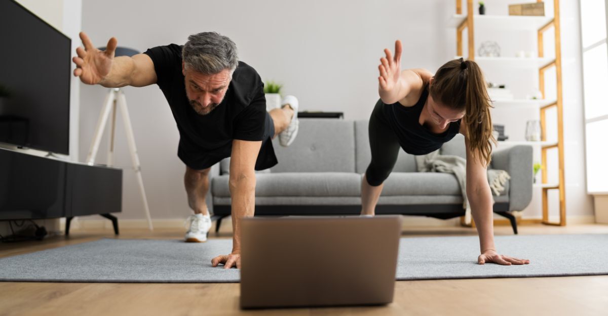 Un uomo e una donna si allenano a casa seguendo degli esercizi da palestra al computer