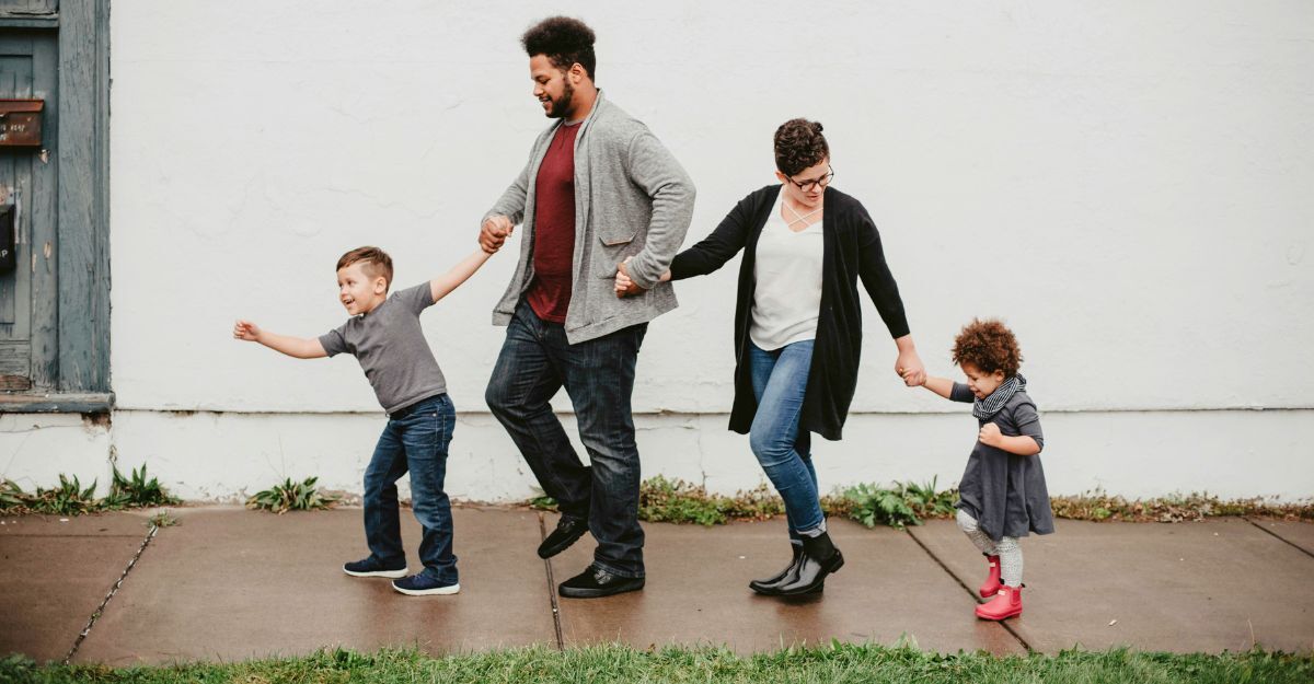 Due genitori con due figli per mano che stanno camminando