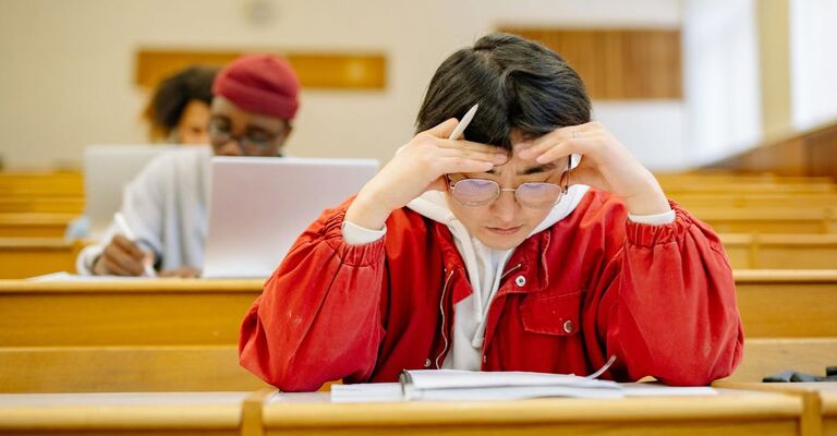 Aula studio di un'università con primo piano su una persona che studia concentrata