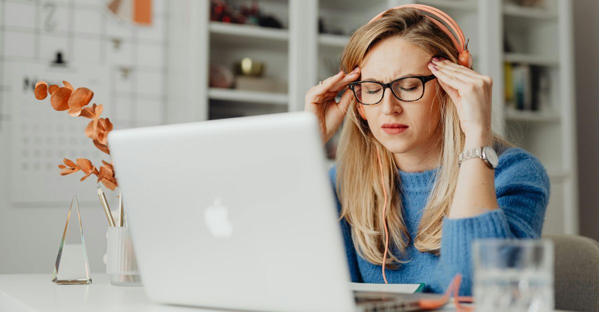 Donna davanti la computer che si tocca le tempie