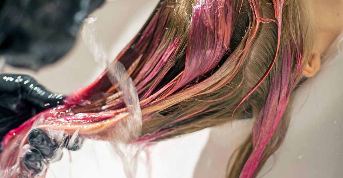 Testa di ragazza bionda con capelli con alcune ciocche tinte di fucsia al lavaggio