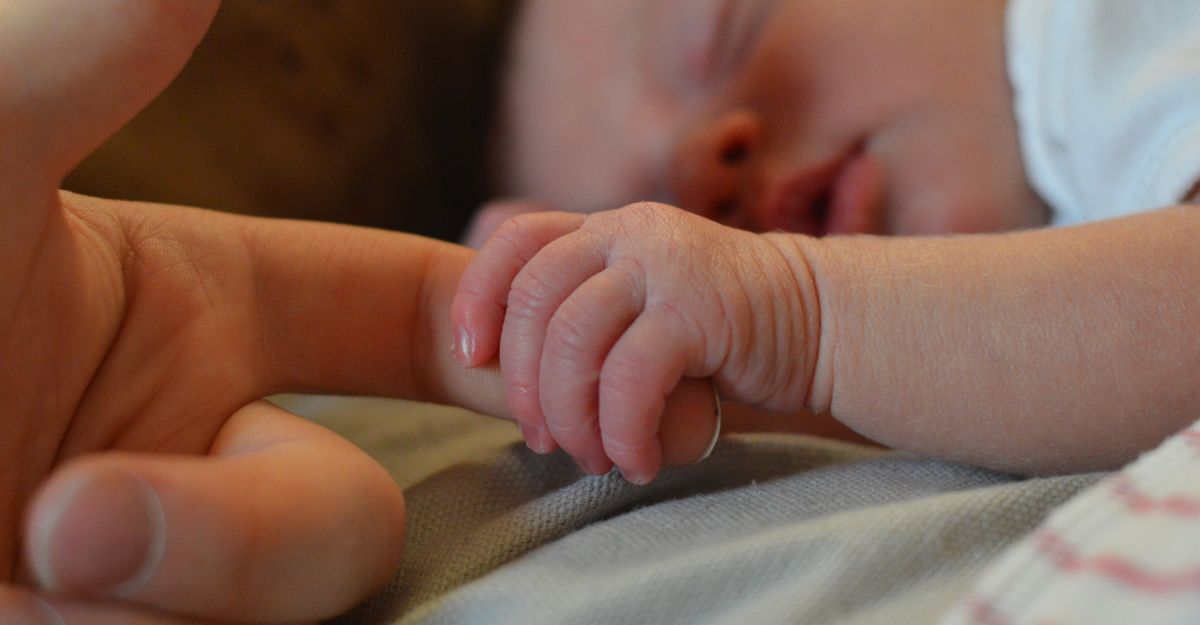 Un neonato tiene il dito della madre