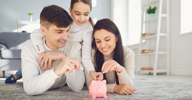 mamma, papà e figlia mettono monetine in un salvadanaio