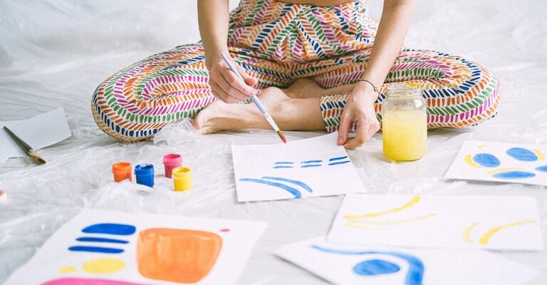 Ragazza seduta per terra che dipinge con gli acquerelli