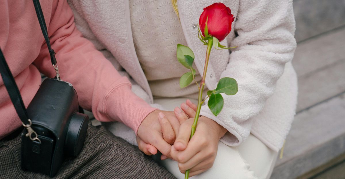 Mani di innamorati intrecciate a una rosa