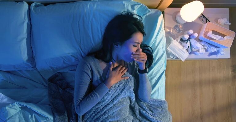 Donna sdraiata sul letto che tossisce durante la notte