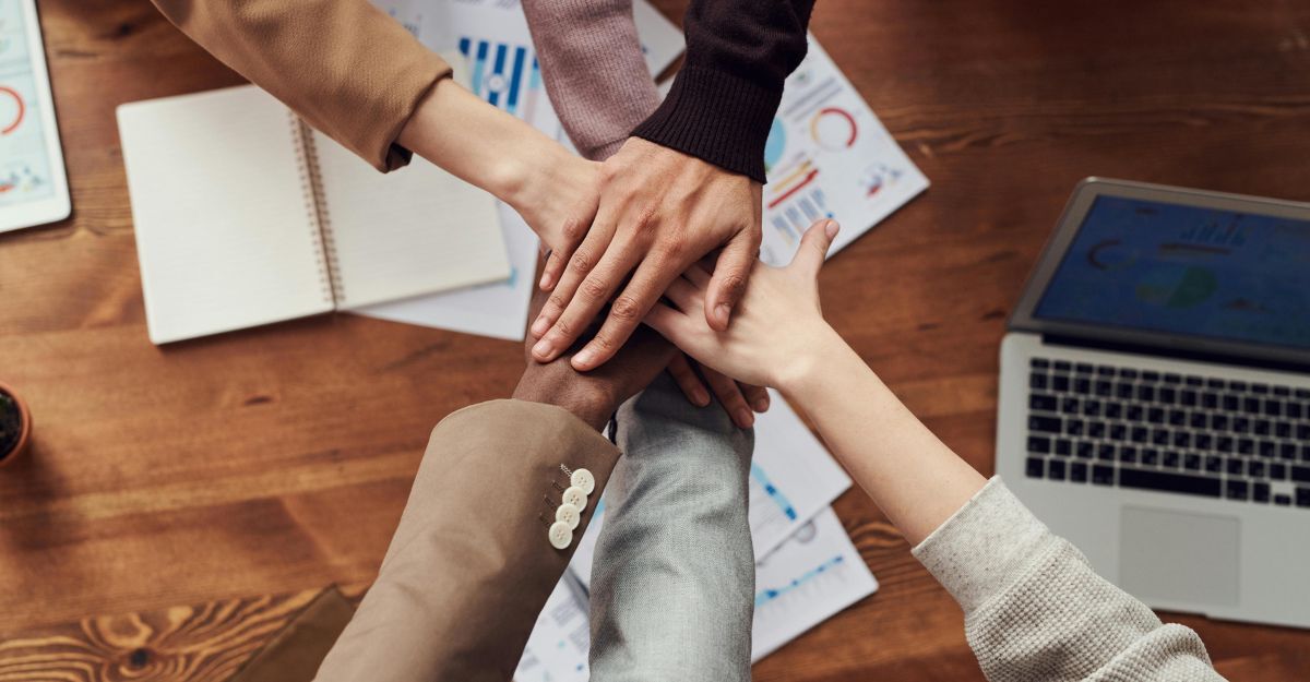 Tante mani che si sovrappongono sopra una scrivania d'ufficio