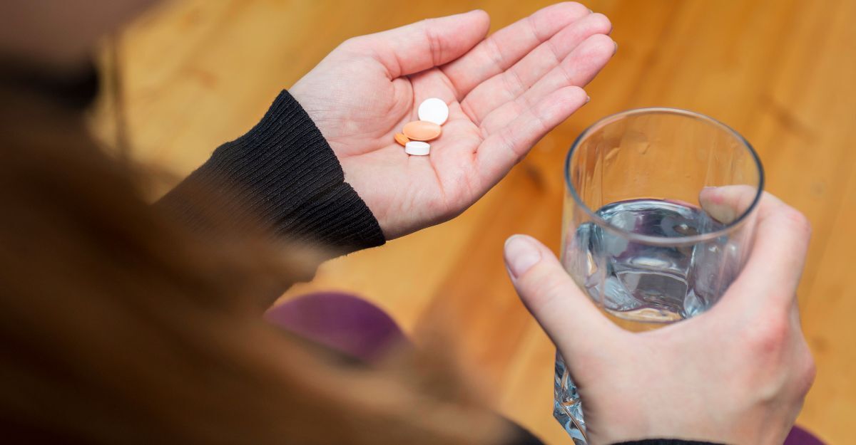 donna prende 2 pastiglie con un bicchiere d'acqua