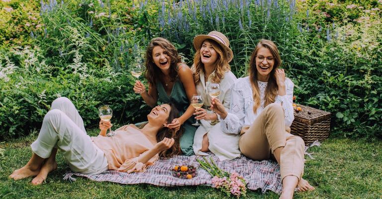 Un gruppo di quattro amiche che festeggia insieme su un prato con un picnic