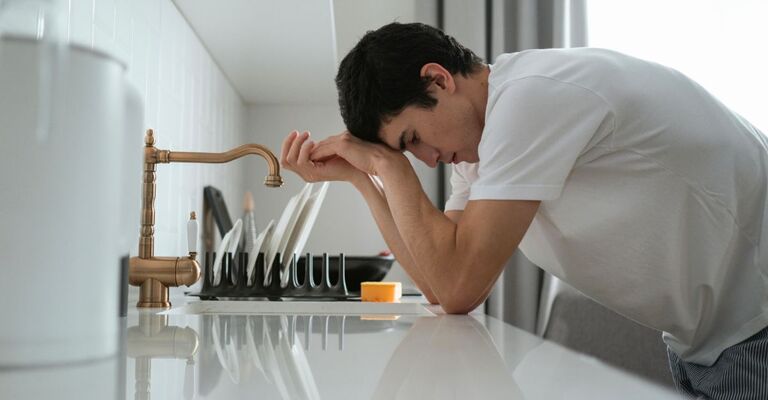 Ragazzo sofferente che si appoggia al bancone della cucina