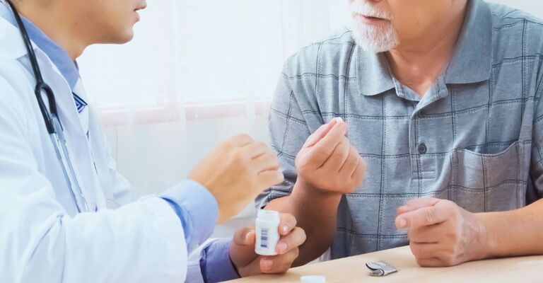 Un signore anziano parla con il medico nel prendere una pastiglia