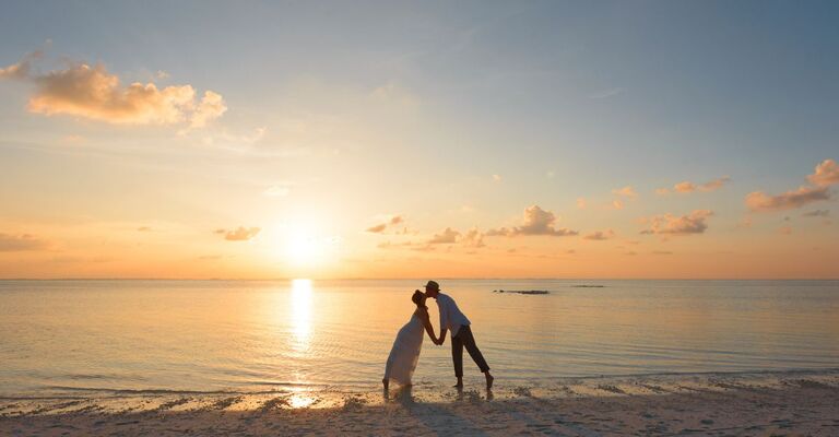 Una coppia che si bacia al tramonto sulla spiaggia