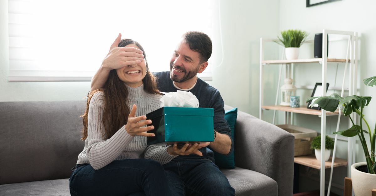 Una ragazza sta aprendo un regalo sul divano assieme al marito