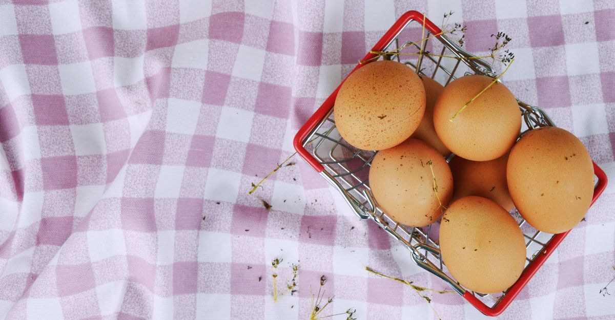 Uova in una cassetta sopra una tovaglia a scacchi lilla e bianca su un prato
