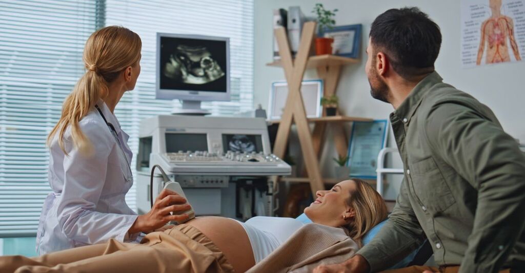 Coppia che osserva il monitor durante un'ecografia addominale per la gravidanza