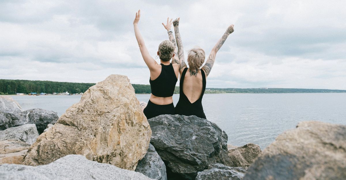 Due ragazze sugli scogli con le braccia alzate