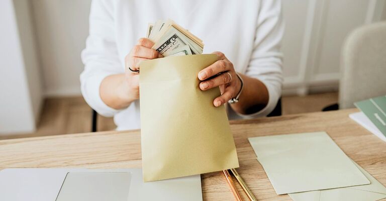 Donna che inserisce soldi in una busta mentre li divide