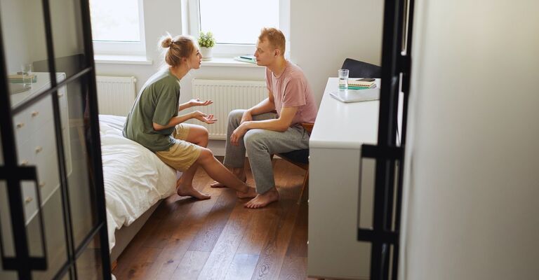 Due ragazzi seduti in camera da letto che si confrontano