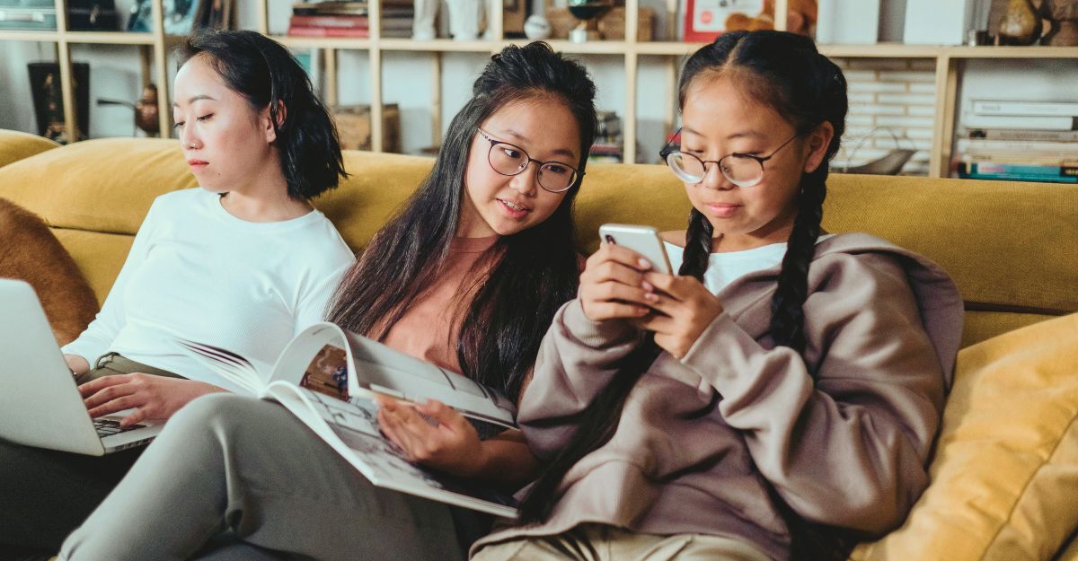 Due sorelle sedute sul divano che guardano il cellulare