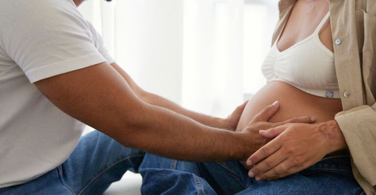 donna incinta e compagno abbracciano bambino nella pancia