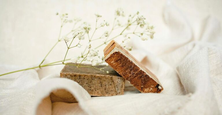 Due saponi solidi su un drappo e circondati da fiorellini (set fotografico)