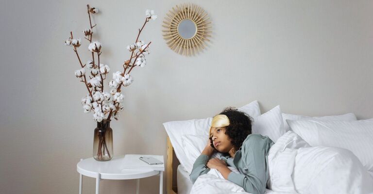 Donna sdraiata nel letto che guarda fuori sconsolata perché non vuole alzarsi